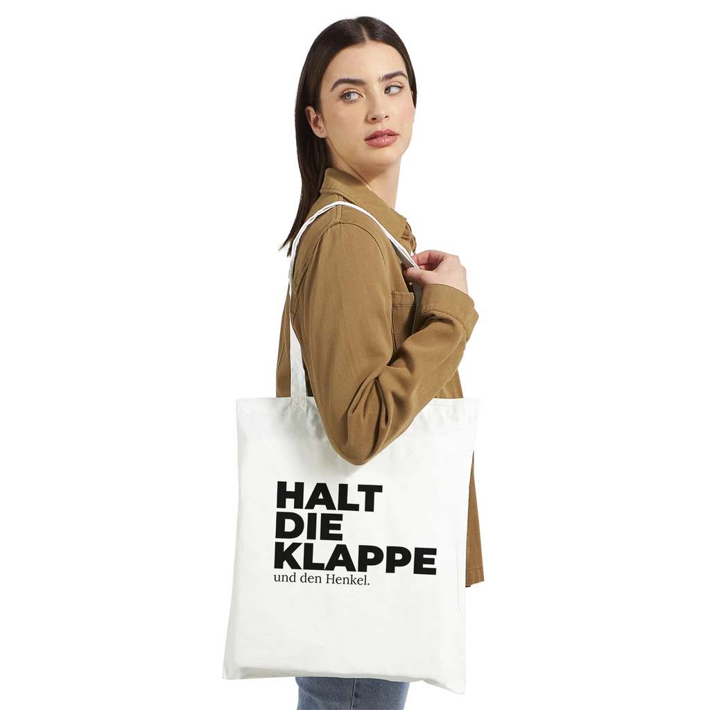Frau trägt weißen Stoffbeutel „Halt die Klappe“ über der Schulter