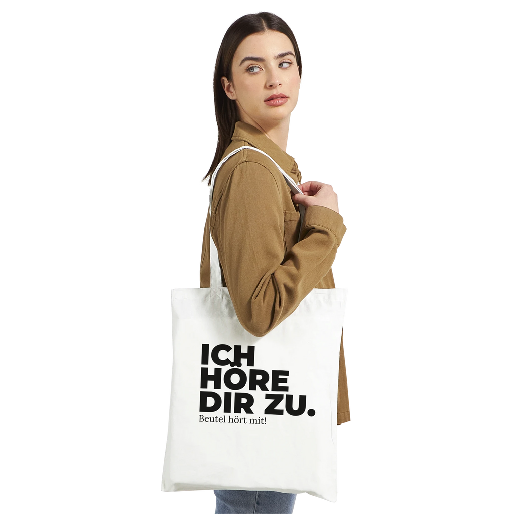 Frau trägt weißen Stoffbeutel „Ich höre dir zu.“ über der Schulter